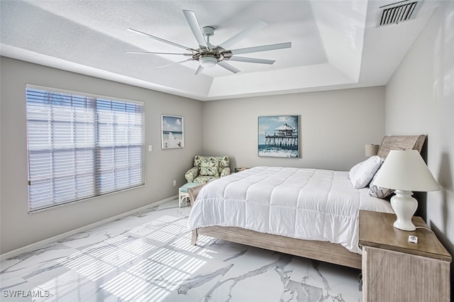 bedroom with a textured ceiling, a raised ceiling, and ceiling fan