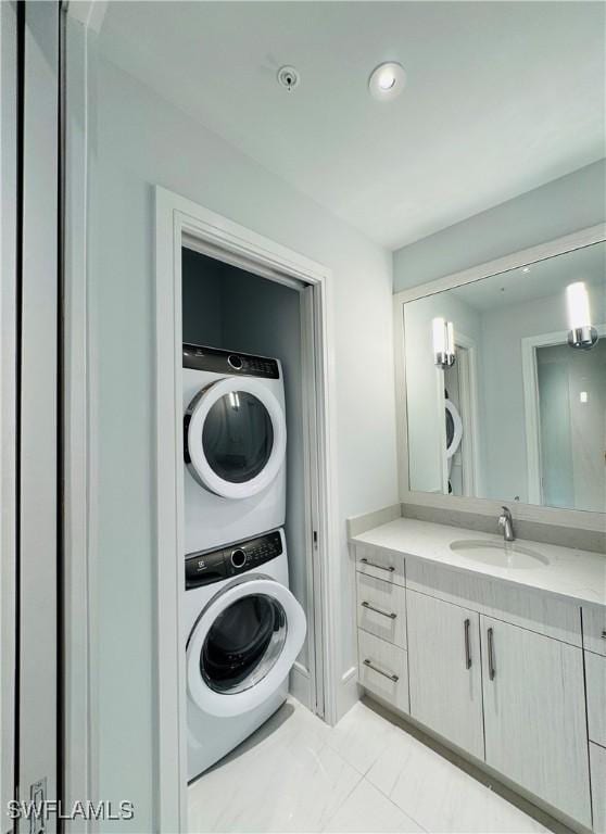 clothes washing area with stacked washing maching and dryer and sink