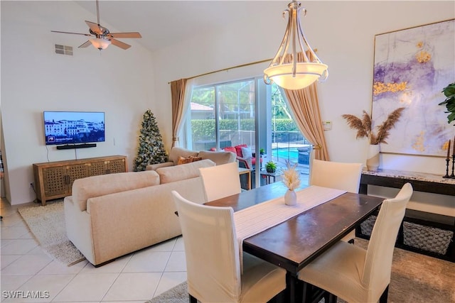 tiled dining room with ceiling fan and a high ceiling