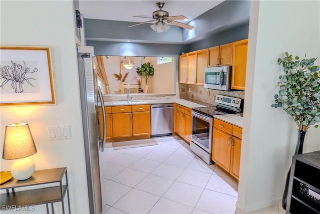 kitchen featuring ceiling fan, sink, backsplash, light tile patterned floors, and appliances with stainless steel finishes