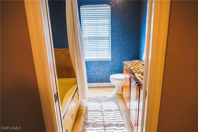 bathroom with tile patterned flooring, vanity, toilet, and a bathtub