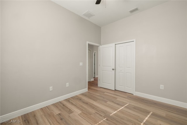 unfurnished bedroom featuring ceiling fan, a closet, and light wood-type flooring