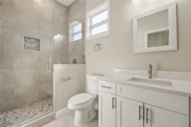 bathroom with tile patterned floors, vanity, toilet, and a shower with door