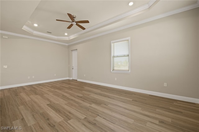 unfurnished room featuring light hardwood / wood-style floors, a raised ceiling, and crown molding