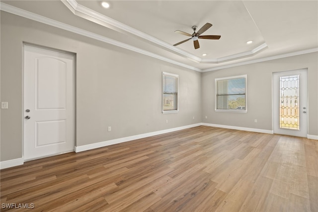 spare room with a tray ceiling, light hardwood / wood-style flooring, and crown molding