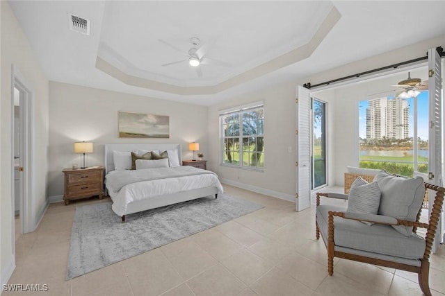 bedroom with light tile patterned floors, a tray ceiling, and ceiling fan