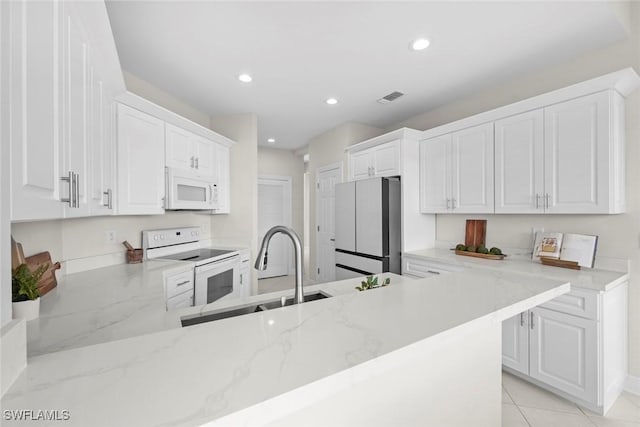 kitchen featuring kitchen peninsula, light stone countertops, white cabinets, and white appliances