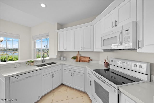 kitchen with white cabinets, white appliances, sink, and light tile patterned floors