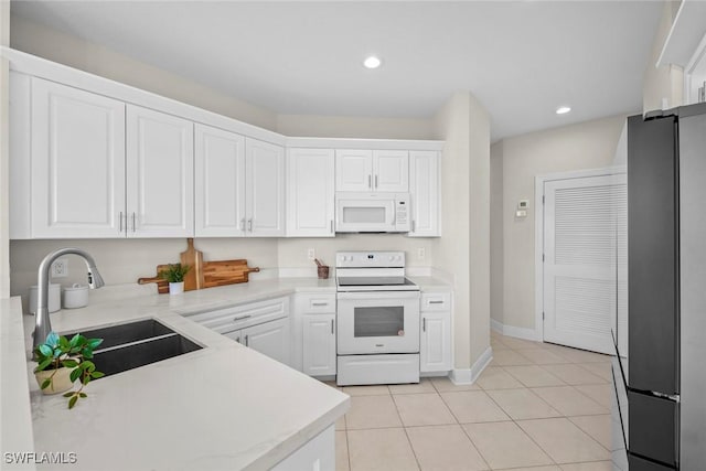 kitchen featuring light tile patterned flooring, white appliances, white cabinetry, and sink