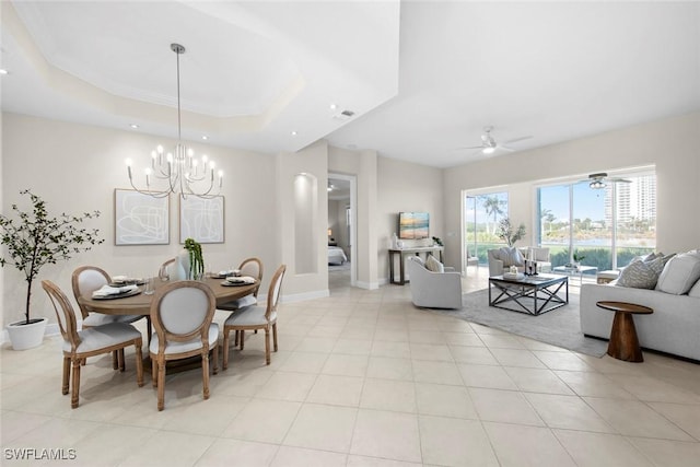 tiled dining area featuring ceiling fan with notable chandelier and a raised ceiling