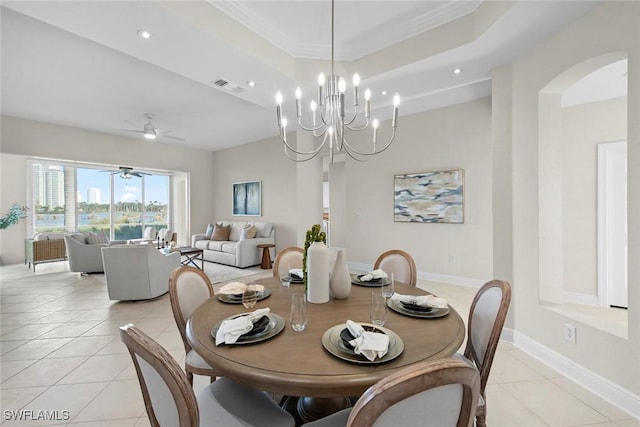 tiled dining room featuring a raised ceiling, ceiling fan with notable chandelier, and ornamental molding