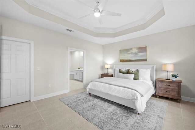 bedroom featuring ensuite bath, ornamental molding, a tray ceiling, ceiling fan, and light tile patterned floors