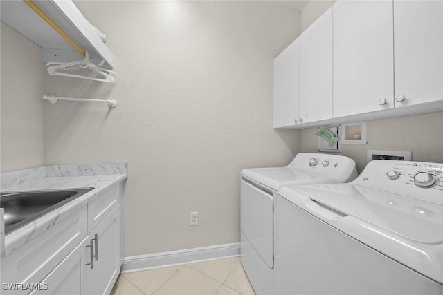 laundry room with washer and clothes dryer, light tile patterned flooring, cabinets, and sink