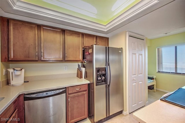 kitchen featuring appliances with stainless steel finishes, ornamental molding, a raised ceiling, and light tile patterned flooring