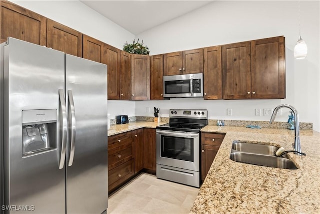 kitchen with light stone countertops, sink, hanging light fixtures, vaulted ceiling, and appliances with stainless steel finishes