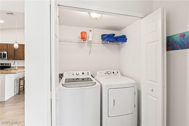 clothes washing area featuring light tile patterned floors and washing machine and clothes dryer