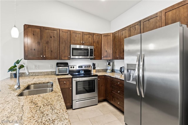 kitchen with pendant lighting, sink, light stone countertops, light tile patterned floors, and stainless steel appliances