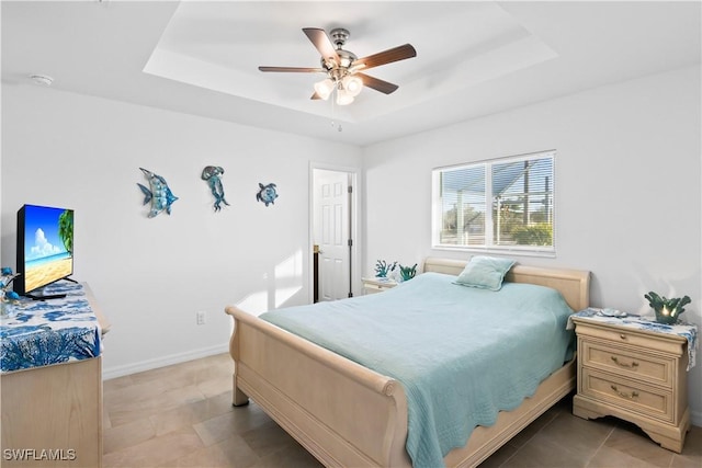 tiled bedroom with a tray ceiling and ceiling fan