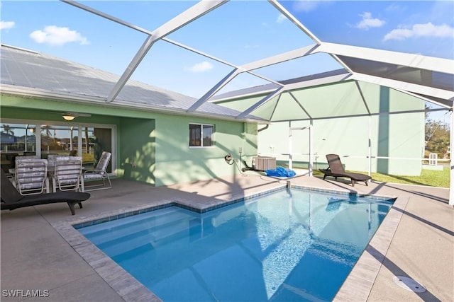 view of swimming pool with glass enclosure, ceiling fan, cooling unit, and a patio