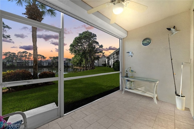 sunroom / solarium with ceiling fan and a water view