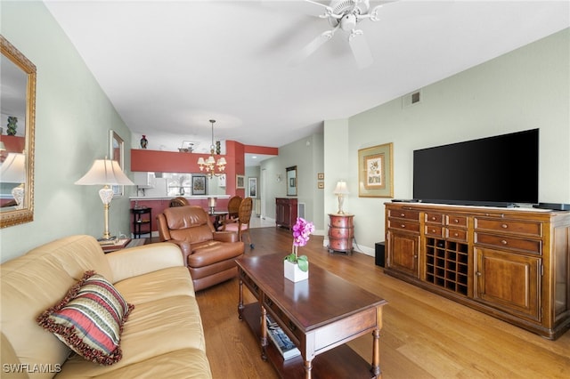 living room featuring ceiling fan with notable chandelier and light wood-type flooring