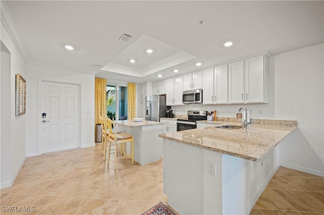 kitchen with white cabinets, sink, kitchen peninsula, a breakfast bar area, and stainless steel appliances