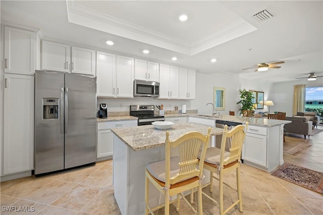 kitchen with a breakfast bar, kitchen peninsula, stainless steel appliances, and a tray ceiling