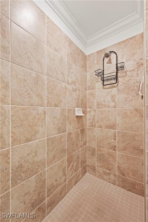 bathroom featuring a tile shower and crown molding