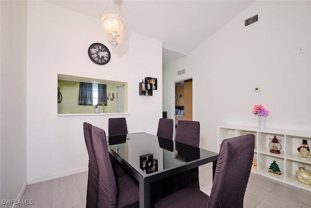 dining area featuring sink, light hardwood / wood-style floors, and vaulted ceiling