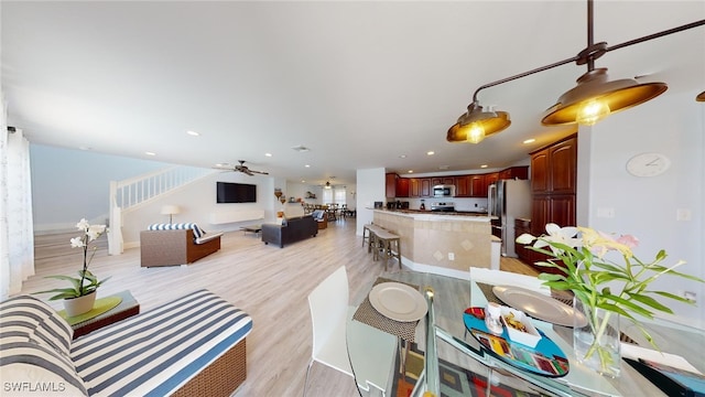 living room with ceiling fan and light hardwood / wood-style flooring