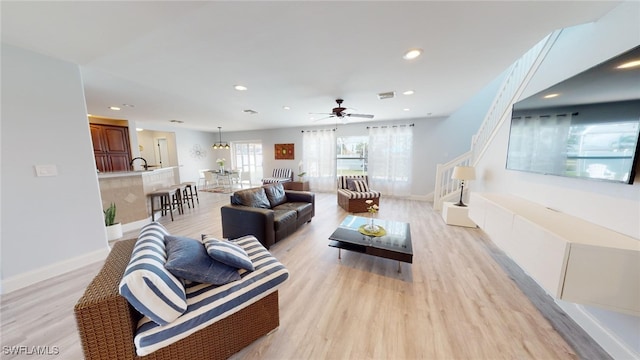 living room with ceiling fan, light wood-type flooring, and sink