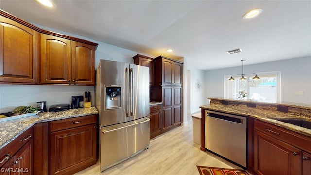 kitchen featuring appliances with stainless steel finishes, decorative light fixtures, an inviting chandelier, light hardwood / wood-style floors, and light stone counters