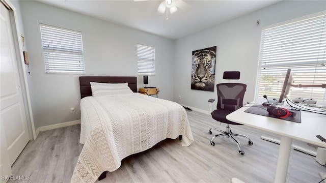 bedroom with ceiling fan, light hardwood / wood-style floors, and multiple windows