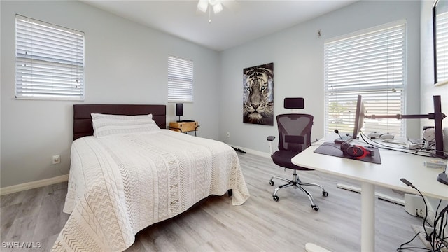 bedroom featuring ceiling fan, multiple windows, and light hardwood / wood-style floors