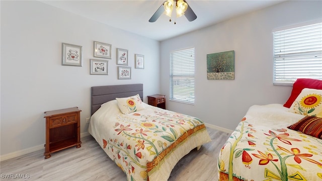 bedroom featuring ceiling fan, multiple windows, and light hardwood / wood-style floors