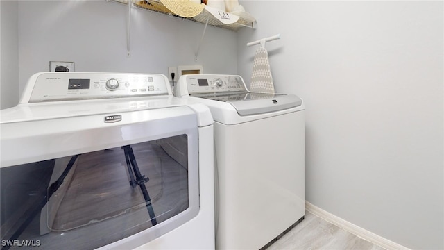 laundry area with washer and dryer and light hardwood / wood-style floors