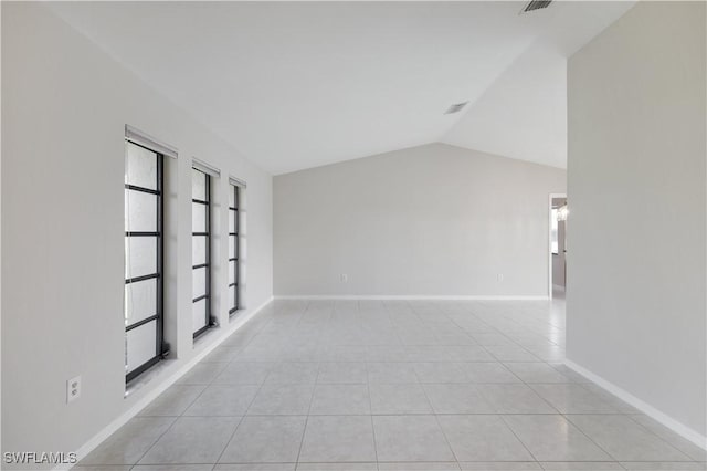 spare room featuring light tile patterned flooring, a wealth of natural light, and vaulted ceiling