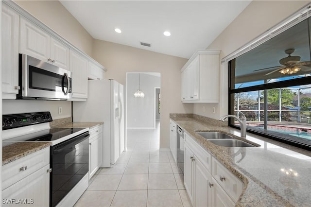 kitchen with light stone countertops, white cabinetry, sink, stainless steel appliances, and vaulted ceiling