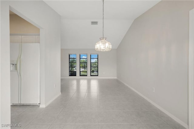 tiled empty room with lofted ceiling and a notable chandelier