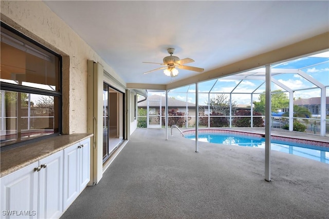 view of pool featuring glass enclosure and ceiling fan