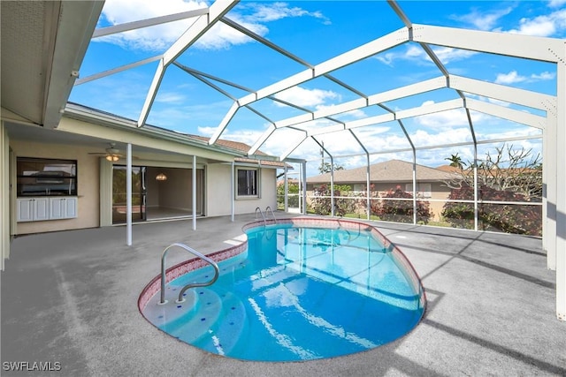 view of pool with glass enclosure, ceiling fan, and a patio area