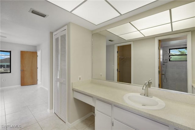 bathroom featuring tile patterned flooring, vanity, and tiled shower