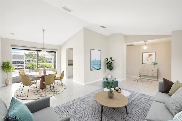 tiled living room featuring lofted ceiling and a chandelier