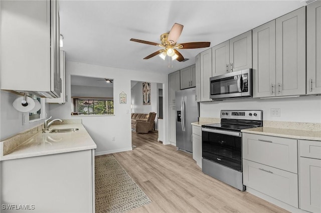 kitchen with ceiling fan, sink, light hardwood / wood-style floors, gray cabinets, and appliances with stainless steel finishes