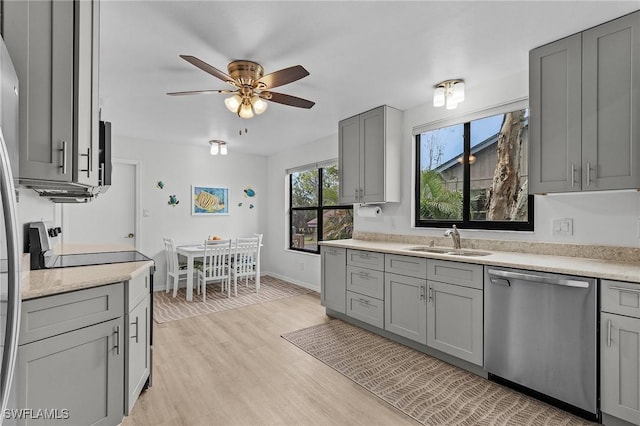 kitchen featuring gray cabinetry, sink, light hardwood / wood-style flooring, stainless steel dishwasher, and ceiling fan