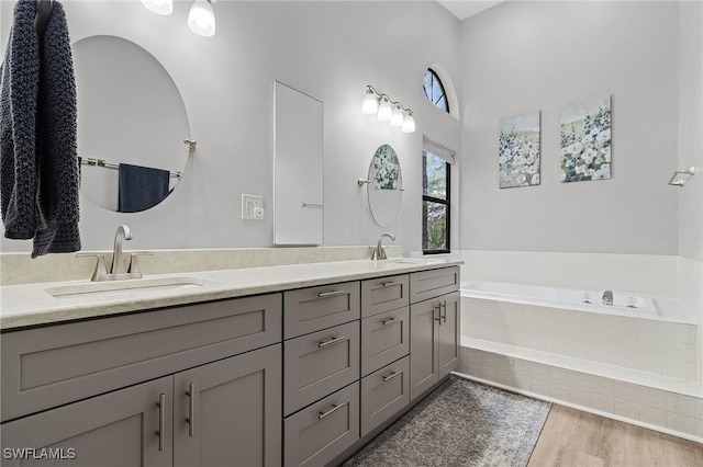 bathroom with vanity, hardwood / wood-style flooring, and tiled tub