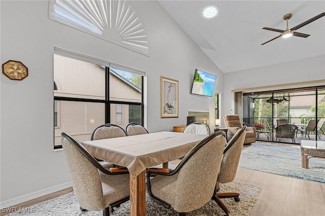 dining room featuring light hardwood / wood-style floors, high vaulted ceiling, and ceiling fan