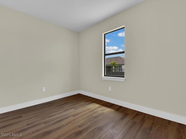 spare room with baseboards and wood finished floors