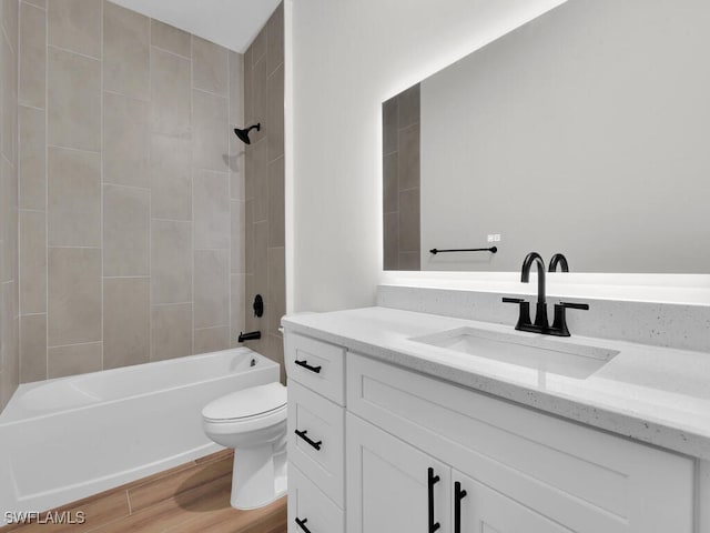 bathroom featuring toilet, vanity, wood finished floors, and shower / bathing tub combination