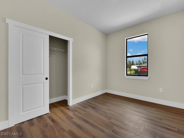 unfurnished bedroom with a closet, baseboards, and wood finished floors